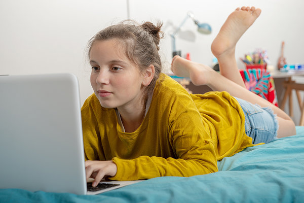 Mädchen auf dem Bauch liegend am Laptop