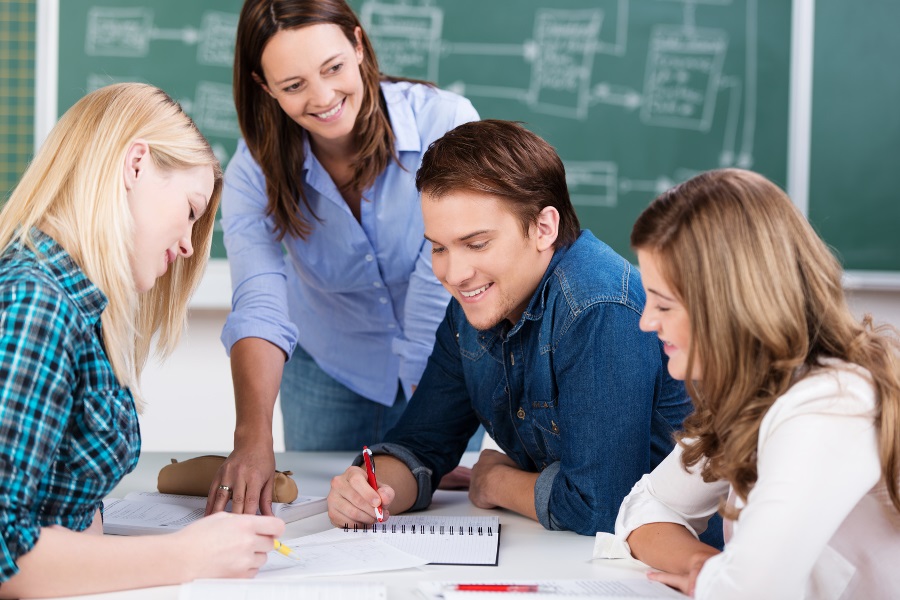 Eine Lehrerin arbeitet mit 2 Schülern an einer Aufgabe.