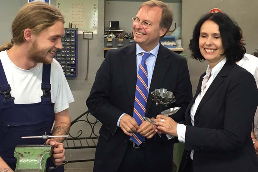 Thomas Rachel MdB (mitte) zu Besuch im "lernen fördern Kreisverband Rhein-Sieg. Rechts von ihn steht ein Auszubildender an einem Schraubstock. Links von ihm steht eine Frau.