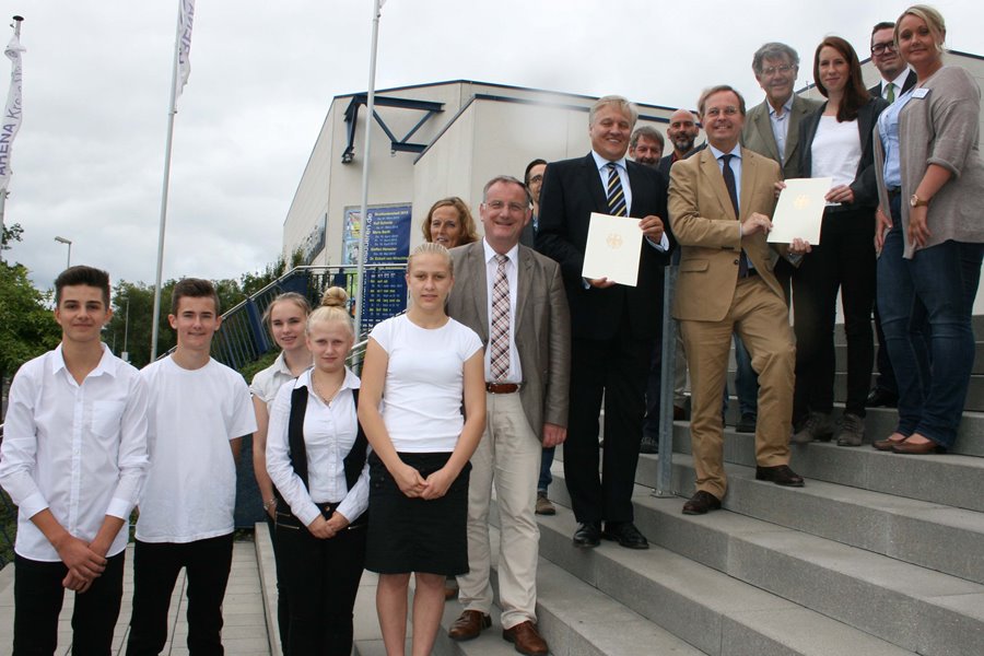 Gruppenbild von der Bescheidübergabe bei der Dürener Gesellschaft für Arbeitsförderung. Auf dem Foto stehen 15 Personen auf einer Treppe.